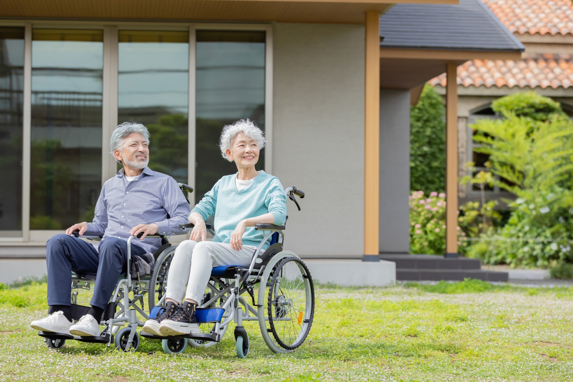 住居の前で車椅子に乗るシニア夫婦